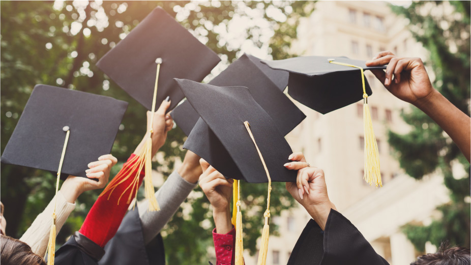 Hands holding graduation caps up high in celebration